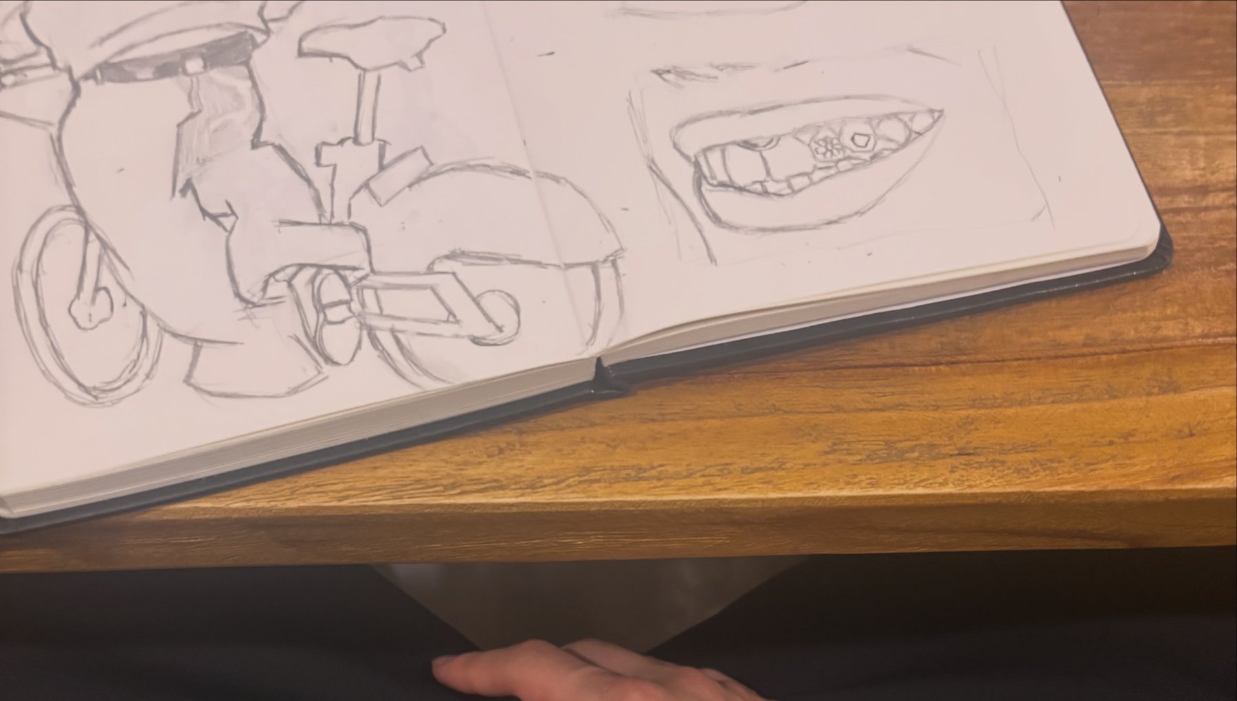 An open sketchbook with pencil drawings of a drum kit and a face.