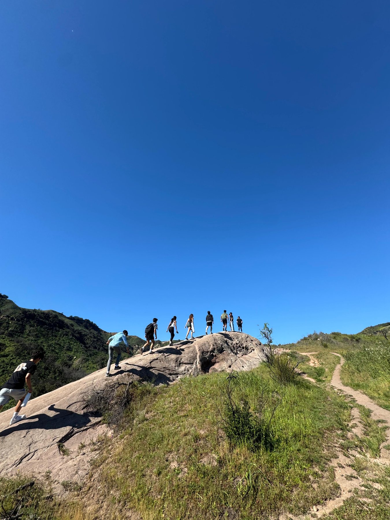 Friends hiking across a rocky ridge beneath a blue sky.